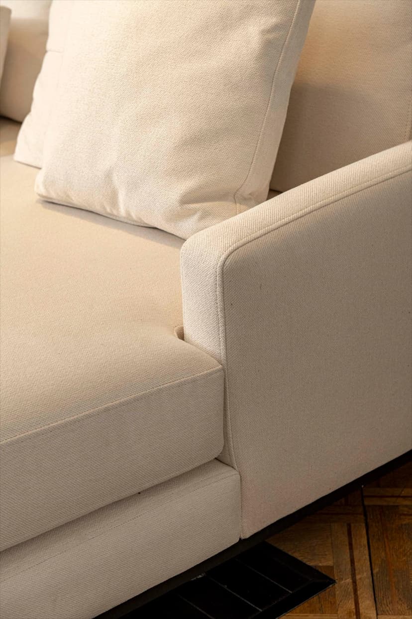 Detalle de sofá tapizado en tela color crudo con almohadones a juego